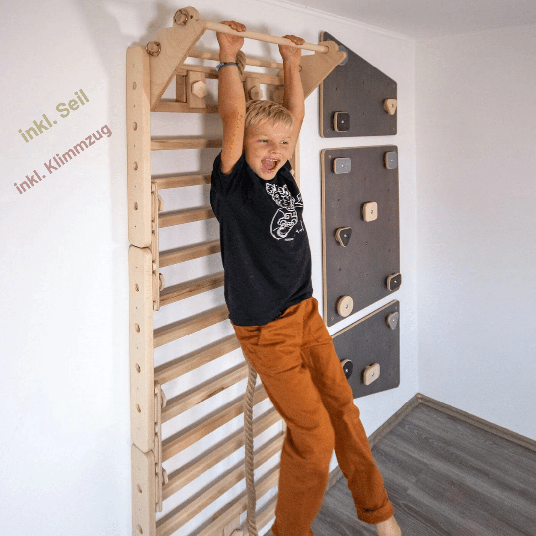 Kind an der Klimmzugstange des LOOPO JUNGLE neben einer Kletterwand
